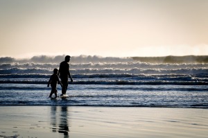 Man and boy walking along water's edge
