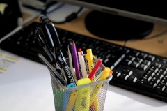 container of pens, pencils, and highlighters in front of a computer keyboard