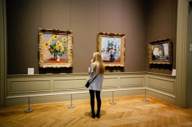 Woman looking at Van Gogh Sunflower painting in an art museum