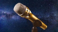 Gold microphone on a midnight blue cloudy, starry background 