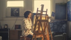 Woman artist working at an easel in front of a window