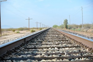 Train tracks converging at a point on the horiaon with a blue sky