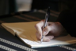 A hand writing with a pen in a journal